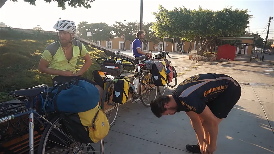Riders and their loaded bikes taking a break in a town square.