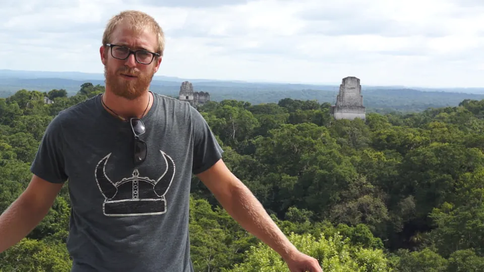 A rider on top of a temple at Tikal, with more temples rising out of the jungle behind him.