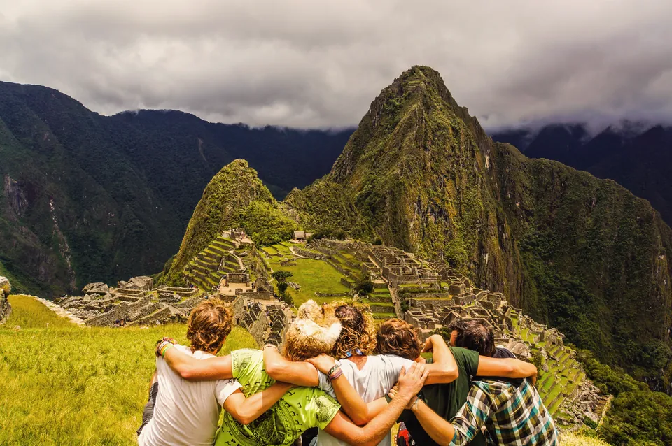 Five riders seen from behind, looking down over Machu Picchu.